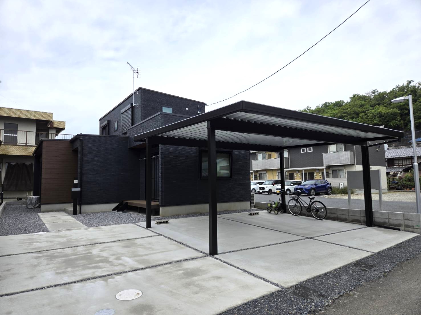 土間はｺﾝｸﾘｰﾄにして間に砂利を入れ、2台用のｶｰﾎﾟｰﾄとﾃﾞｯｷを設置しました。
玄関前にスッキリとした機能門柱を設置しました。